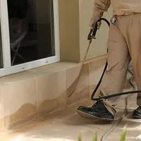 General pest control technician spraying exterior perimeter around a home in Santa Ana, CA